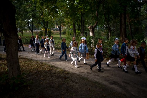 children walking to school down a tree-lined sidewalk