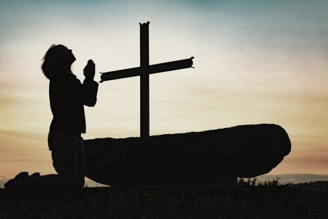 woman kneeling by cross