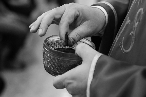 a robed clergy person holds a bowl of ashes, preparing for distribution at an Ash Wednesday service