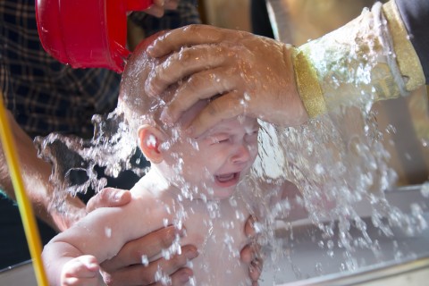 a priest baptizes a baby