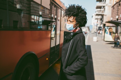 woman in surgical mask waiting for bus