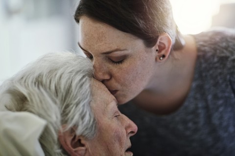 a woman kissing her elderly mother's forehead