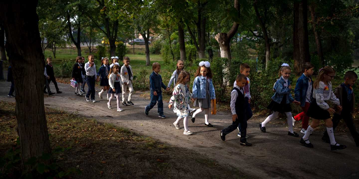 children walking to school down a tree-lined sidewalk