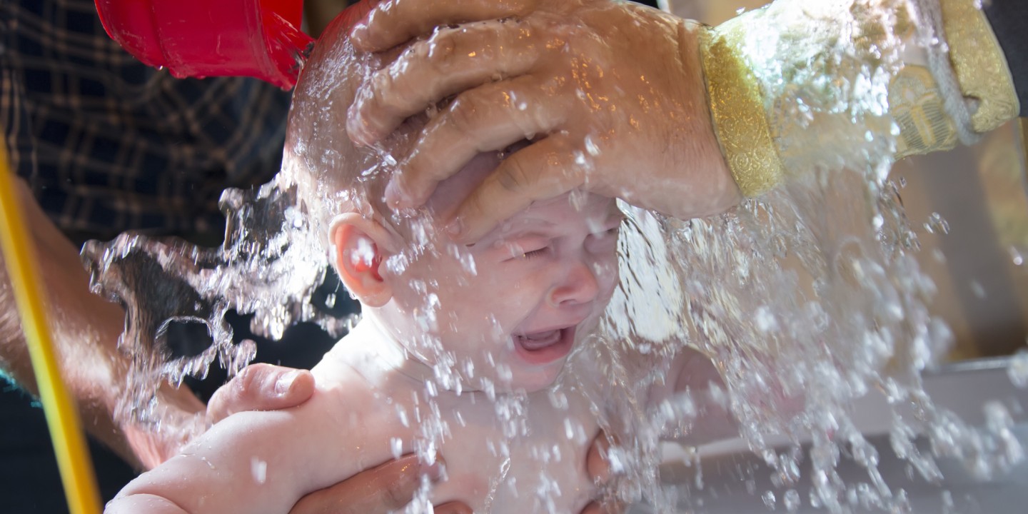 a priest baptizes a baby